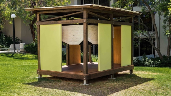 A wooden structure stands on a lawn on Occidental's campus for LAMOA
