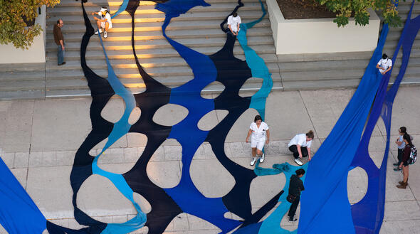 An overhead shot of artists and students putting together the large blue installation as part of Knitting Nation Phase 12