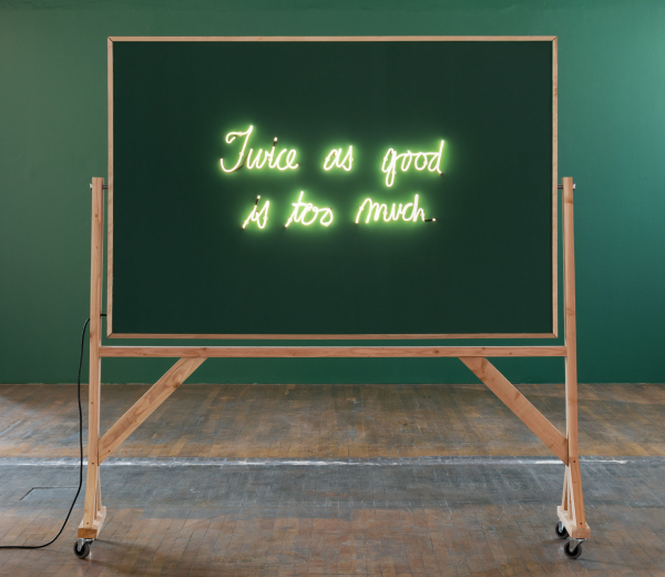 A blackboard that reads "Twice as good is too much" in neon letters