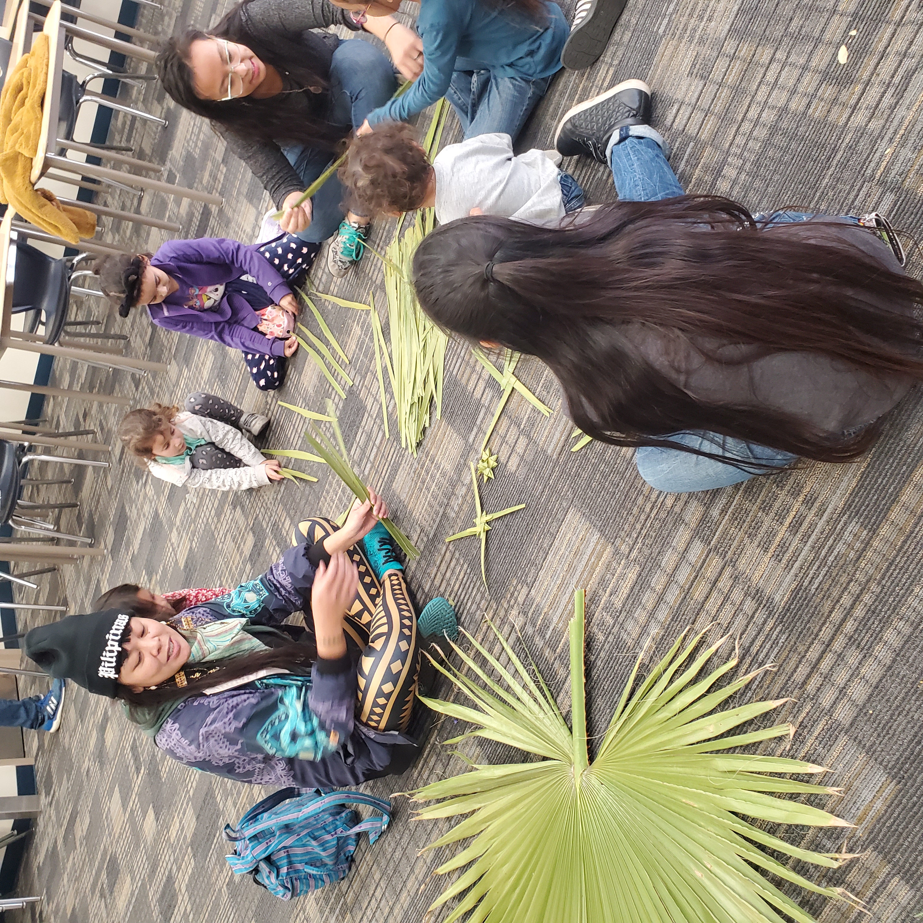 Photo of a group of people sitting holding palm leaves. 