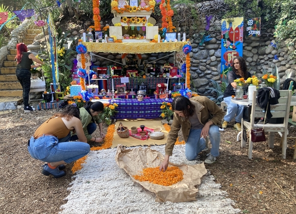 Students arranging flowers at the Highland Park Dia de Los Muertos altar