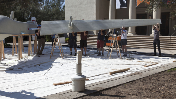 A group of people begin construction on the drone for We Will Show You Fear in a Handful of Dust