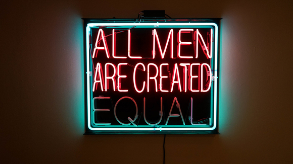 A pink and teal neon sign that reads "all men are created equal"