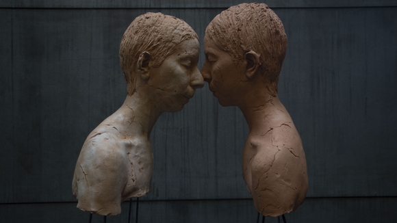 color image of two sculptural busts in profile, with their faces touching