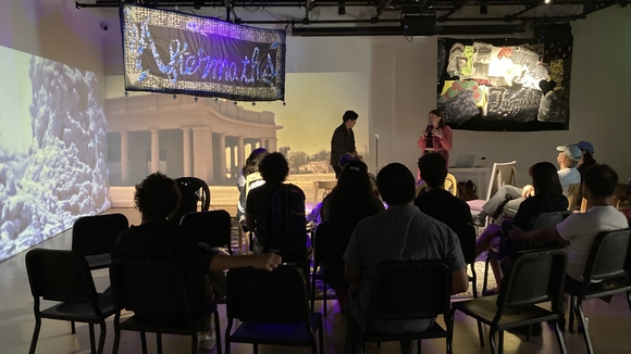 group photo of people sitting in Cauleen Smith's installation with two people speaking on a mic 