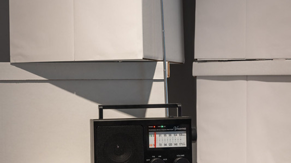 A black radio sits on top of white archival boxes.