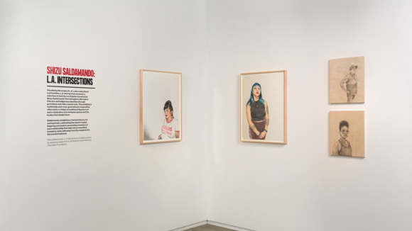 Four portraits from Shizu Saldamando's L.A. Intersections hang on a white wall