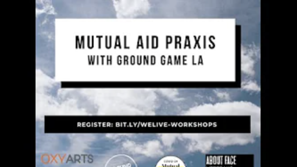 A photo of a cloudy sky in the day time with a textbook stating "Mutual Aid Praxis with Ground Game LA" in front of it.