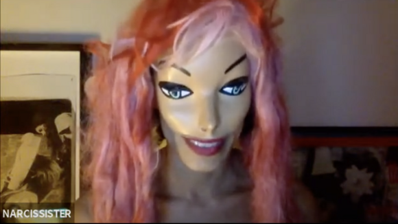 Person wearing a mask that is aesthetically similar to a Barbie doll and a long-hair, pink wig.