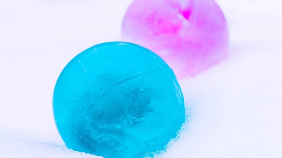 Two colorful frozen balls of water - one is pink and one is blue
