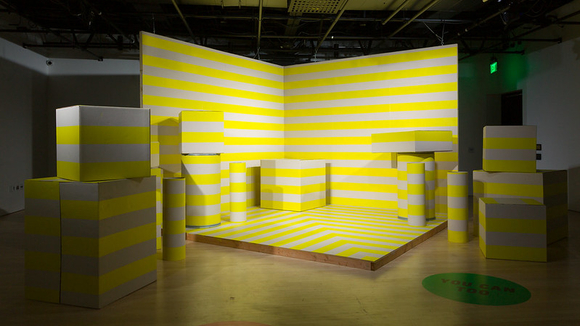 Stage with various sized shapes, all are painted with yellow and white stripes.