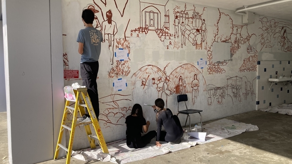 three students with their backs to the camera work on the in-progress Franklin Mural