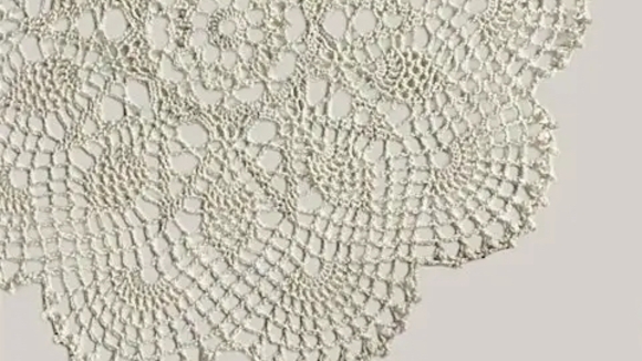 Close up of white lace doily on beige background 