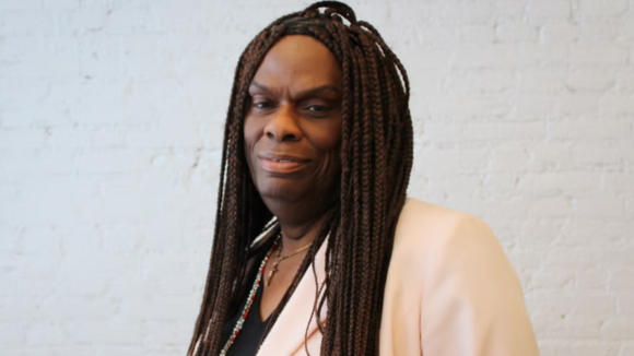 Portrait of Dee Farmer. She is wearing a cream colored shirt and looking into the camera smiling. 