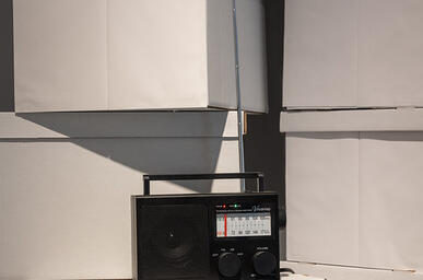 A black radio sits on top of white archival boxes.