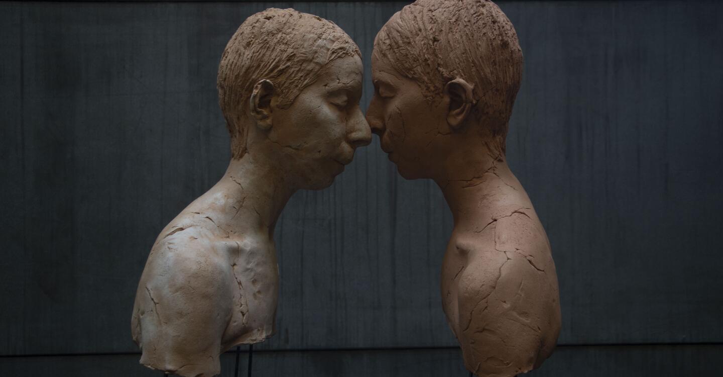 color image of two sculptural busts in profile with their faces touching