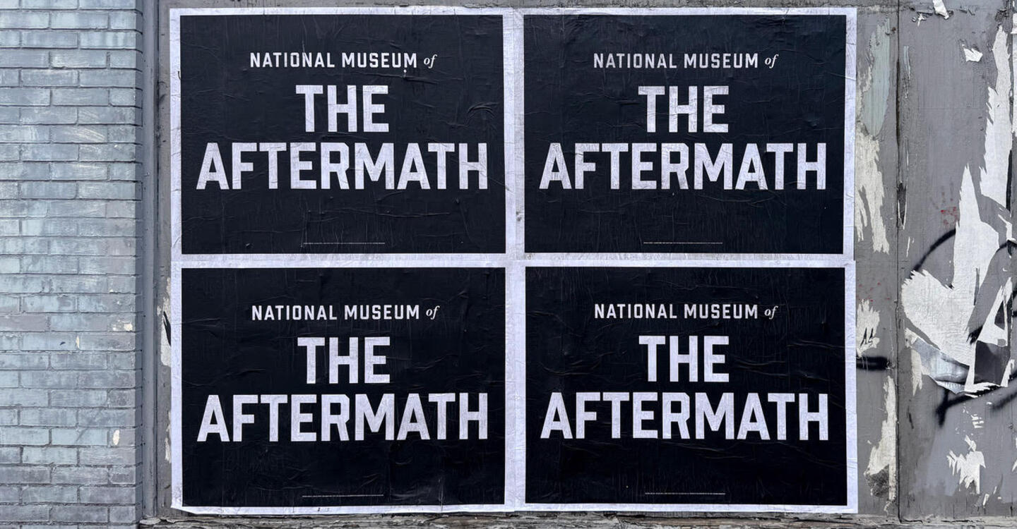 A wall with posters on it. The posters are black and white and read National Museum of the Aftermath 