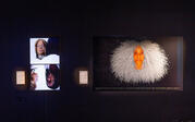 A striking image of a Black woman with white hair on the right and two bright white portraits on the left on a black background