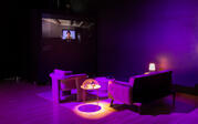 A dark living room setup illuminated by magenta light