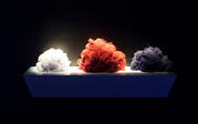 Three piles of red, white, and blue fibers on a shelf against a black background.