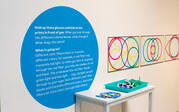 Blue vinyl circle with exhibition text and three prints with various colored lines.