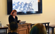 Shizu Saldamando presenting to audience alongside presentation depicting her artwork drawing of a crowd
