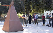 Tzolk’in, a tall, brown pyramid made of metal, in the middle of a courtyard