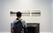 person looking at three side by side black and white photos of a landscape