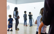 A family looking at 'Double Quadruple Negative Etcetera Etcétera' with children reaching toward the projection and making shadows.