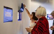 A person lifting a curtain flap to reveal a protection amulet photograph.