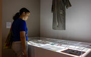 Person viewing "Cosmic Bitcasting" dress hanging above a lightbox of photographs.