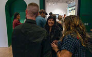 A group of people greeting each other and discussing artwork in the gallery.