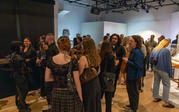 A large crowd of people talking and discussing artwork in the gallery