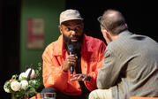 Tavares Strachan sitting and gesturing as he speaks into a microphone to Paul Holdengräber.