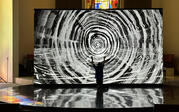 A view of Last Whispers playing on a large screen with the silhouette of a person kneeling and raising their arms on the stage in front.