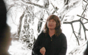 Artist and Oxy MAC Professor Amanda Tasse speaking, lit behind by the screening of Last Whispers.