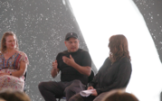 Jonathan Yomayuza gesturing and speaking during the panel talkback as Tasse and Sherman listen.