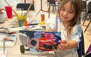 A girl holding her art made with textiles and watercolor.