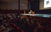 wide shot of Ed Ruscha and Paul Holdgengraber on stage, with Ruscha's work projected behind them