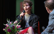 medium full shot Miranda July on stage with Paul Holdengraber
