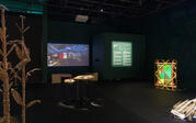 The film El Secreto del Rastro projected onto a dark wall in the gallery, featuring a child laying on the ground. 