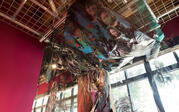 Close up of Alicia Piller's "Blood and Breath" installation on ceiling, with tulle drapery and collaged newspapers. 