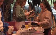 People gathering magazines from a table. 