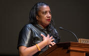 Robin Coste Lewis speaks at a podium with a passionate and serious expression.