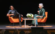 Full view of Robin Coste Lewis and Alexandra Grant sitting on stage, heads thrown back in laughter.