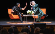 Full view of Robin Coste Lewis and Alexandra Grant sitting on stage, high-fiving.