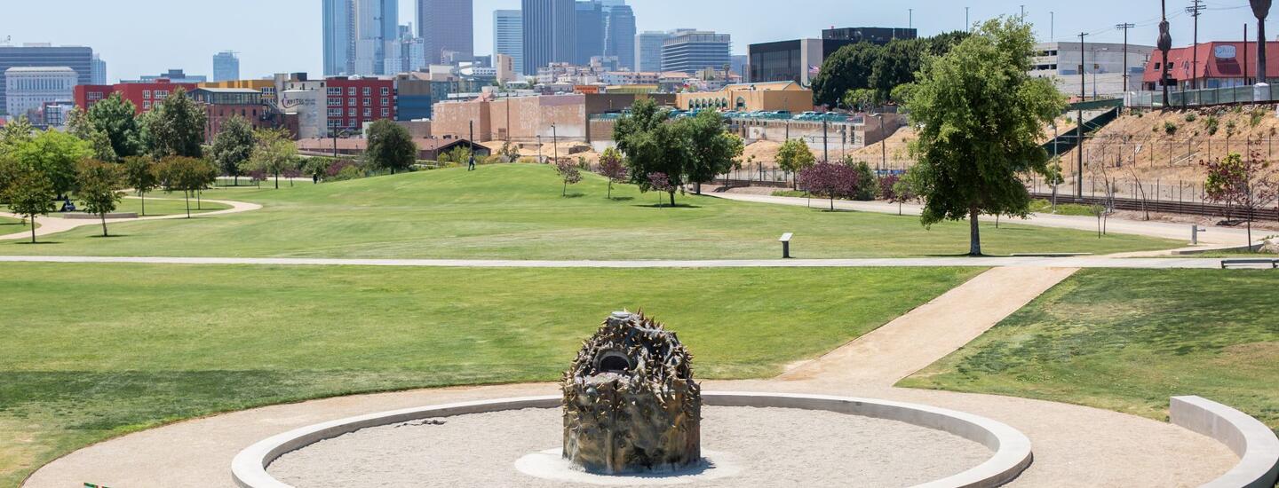 A beehive oven stands in LA Historic Park, with the city scape of downtown Los Angeles in the background