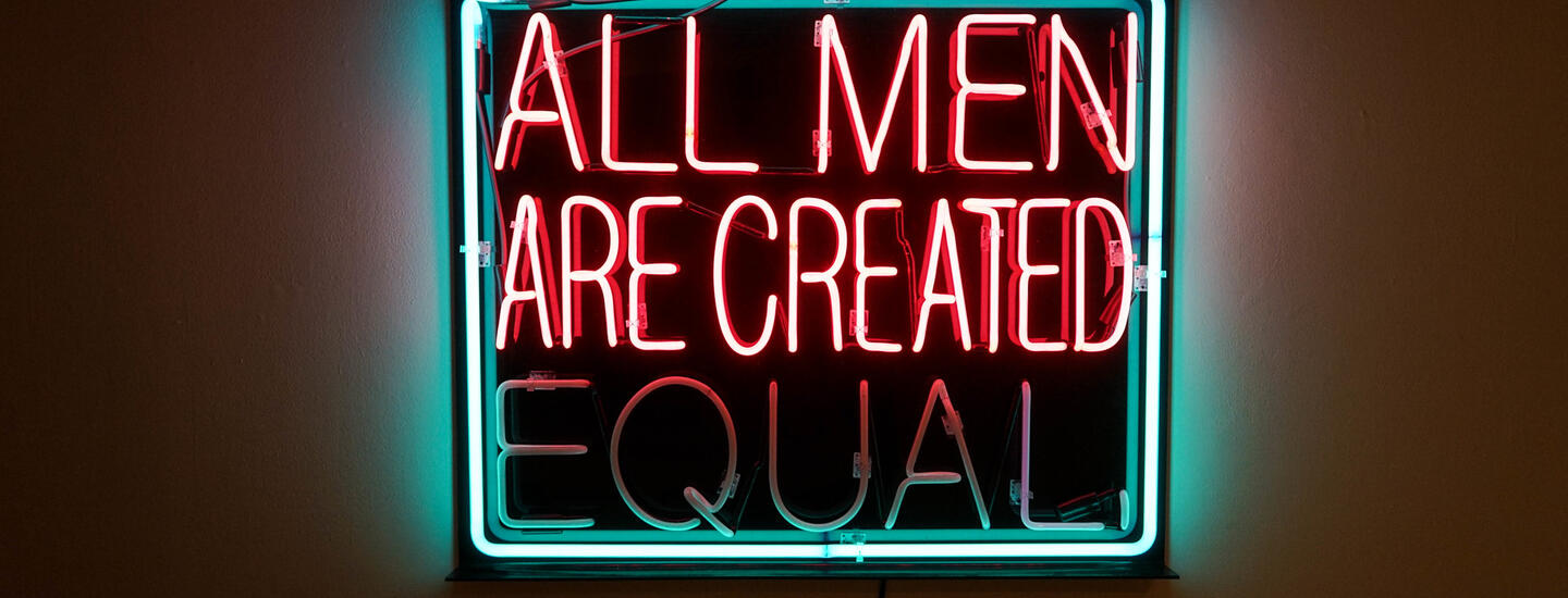 A pink and teal neon sign that reads "all men are created equal"