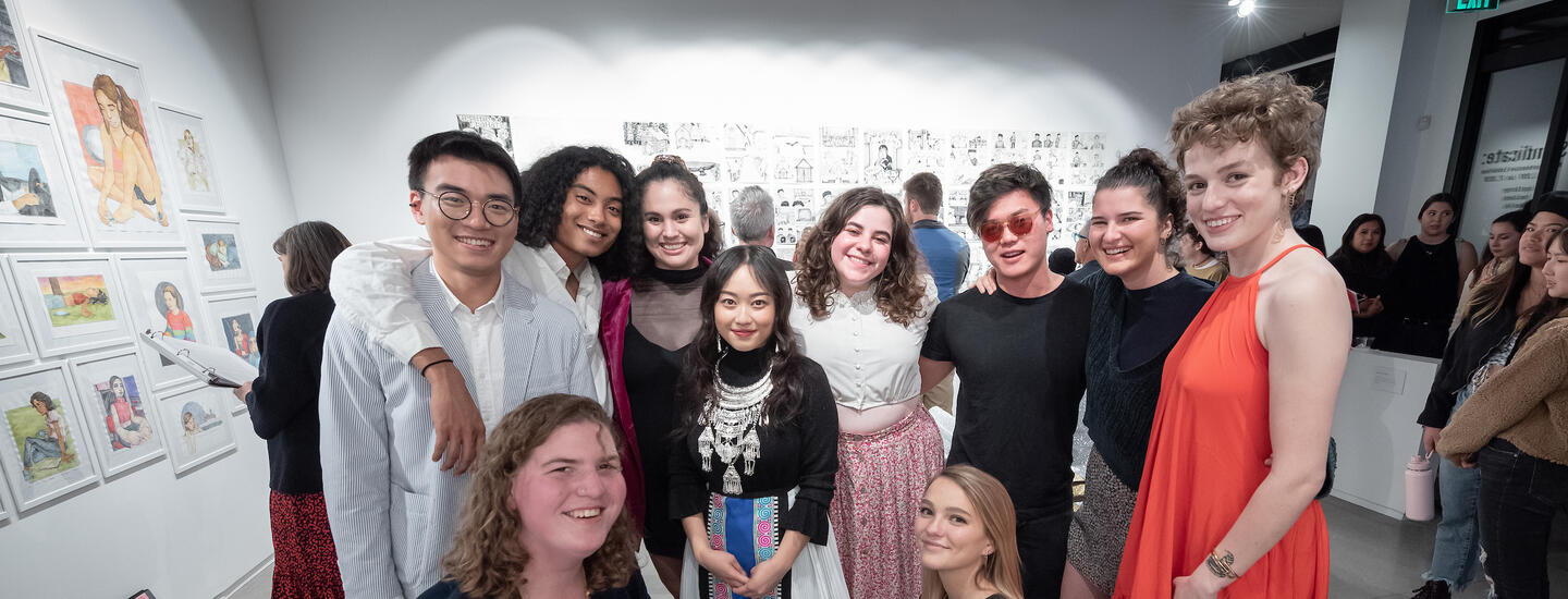 Ten students from the class of 2019 stand smiling at their senior comp exhibition opening