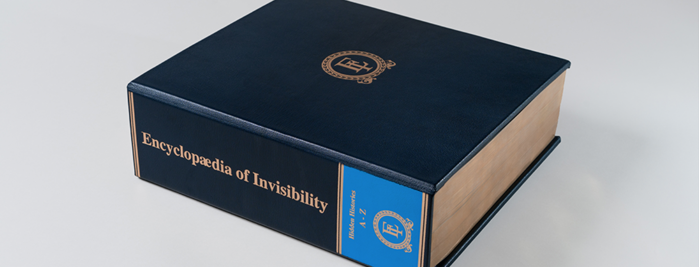 Photo of a blue leather bound book on a light grey background. 